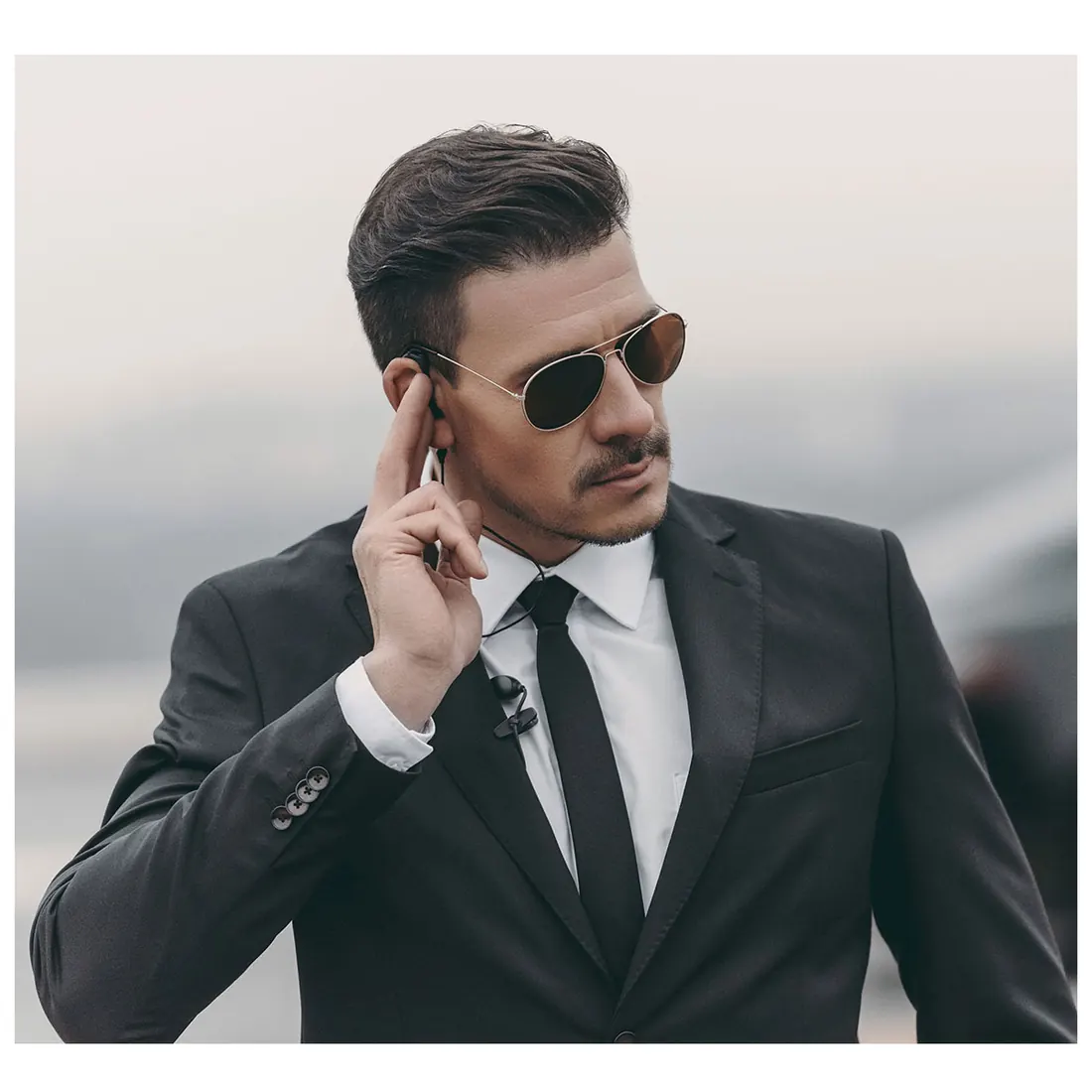 Sicherheitsmitarbeiter im Anzug mit Sonnenbrille und Ohrhörer